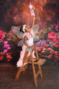 girl reaches on a ladder at a fairy photoshoot in houston